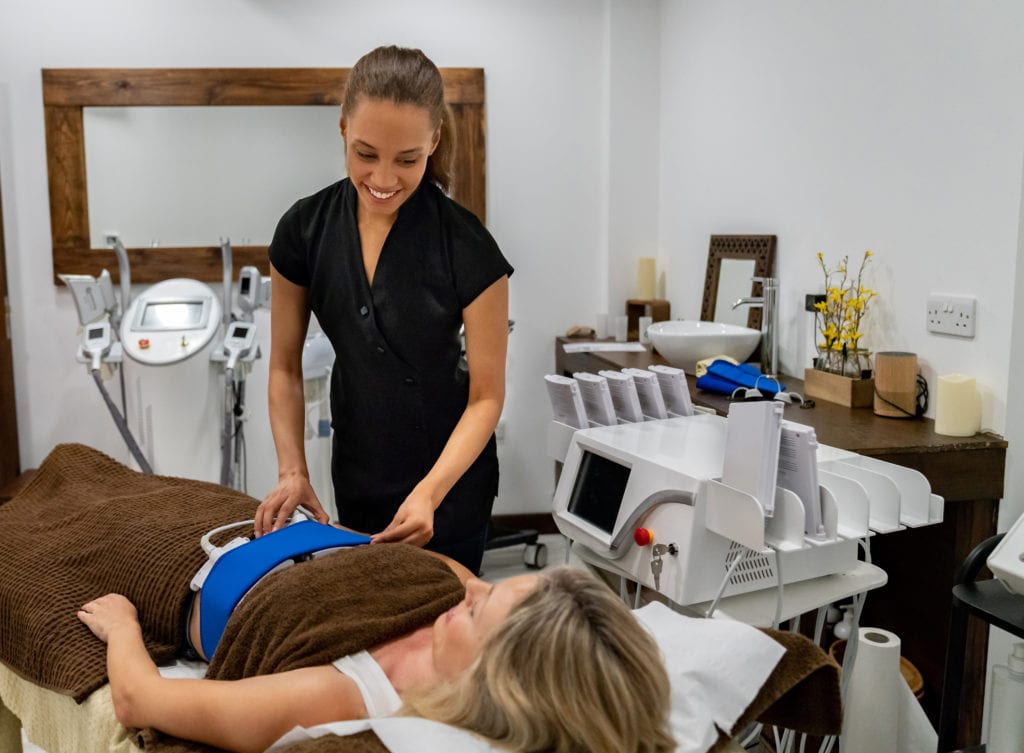 beautician working at a spa doing a lipo massage to a woman - CoolSculpting - Vanquish - Kybella