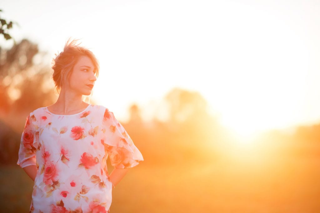 Young woman in floral shirt in against a strong exposure to sunlight