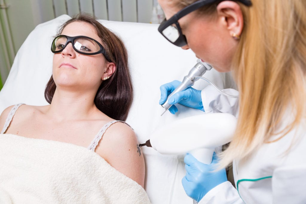 Removing tattoo on arm of young woman by medical laser.
